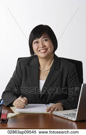 business woman sitting at desk smiling View Large Photo Image Stock Photography - business woman sitting at desk smiling. Fotosearch