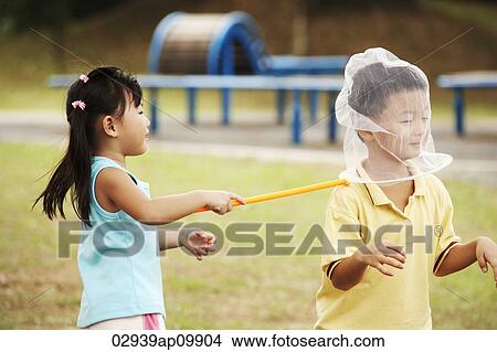 girl catching a boy with butterfly net View Large Photo Image Picture - girl catching a boy with butterfly net. Fotosearch