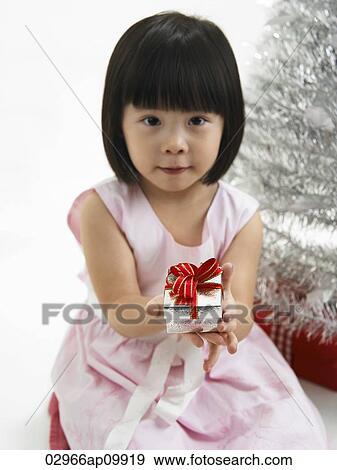 girl holding present in front of christmas tree View Large Photo Image Stock Photo - girl holding present in front of christmas tree. Fotosearch