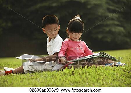 Stock Photo - little boy and girl reading a book outdoors. Fotosearch