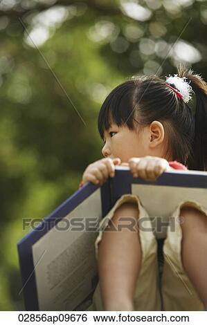 Stock Photograph - little girl reading a book outdoors. Fotosearch