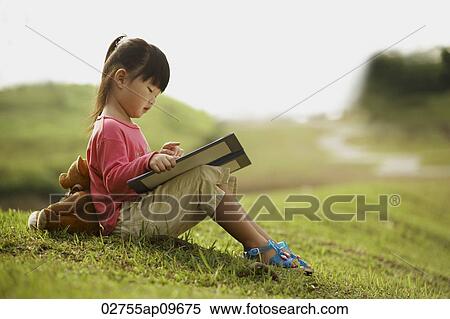 little girl reading a book outdoors View Large Photo Image Stock Photography - little girl reading a book outdoors. Fotosearch