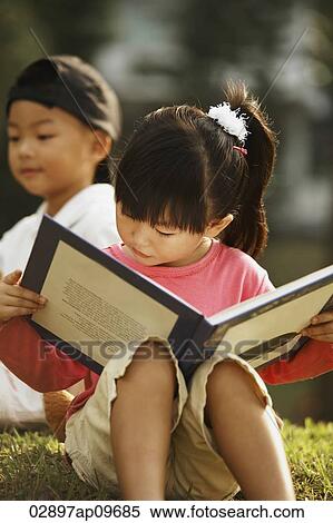 Stock Photography - little girl reading a book outdoors. Fotosearch