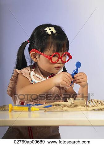 "little girl wearing glasses, examining toy skeleton" View Large Photo Image Stock Photo - "little girl wearing glasses, examining toy skeleton". Fotosearch
