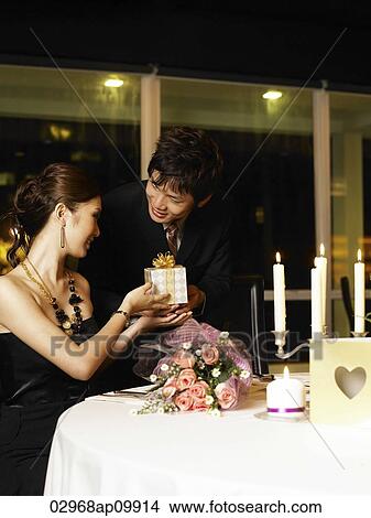 man giving woman a present at a restuarant View Large Photo Image Picture - man giving woman a present at a restuarant. Fotosearch