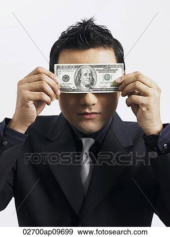 man holding up an American bill against his eyes View Large Photo Image Stock Photo - man holding up an American bill against his eyes. Fotosearch
