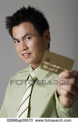 Stock Image - man smiling behind gold credit card. Fotosearch