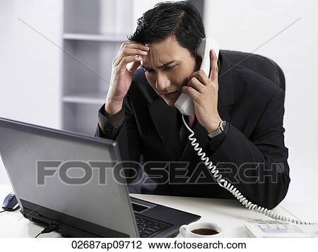 Stock Image - man talking on the phone looking confused. Fotosearch