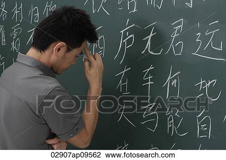 Stock Image - man thinking in front of Chinese characters on chalk board. Fotosearch