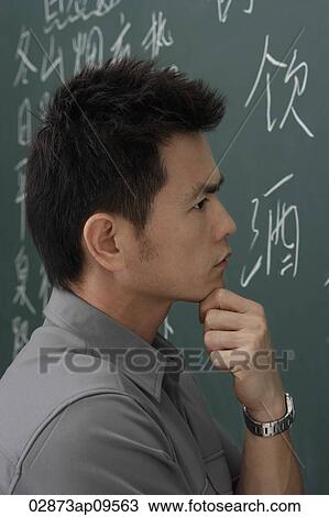 Stock Image - portrait of man thinking in front of chalk board. Fotosearch