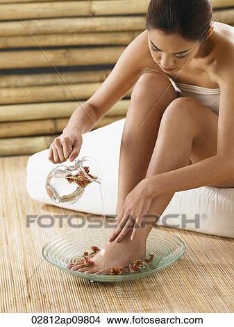 Picture - woman pouring rosewater over her feet. Fotosearch