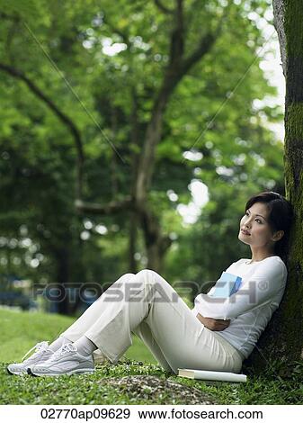 "woman resting against tree, reading" View Large Photo Image Stock Photo - "woman resting against tree, reading". Fotosearch