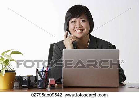 woman sitting at desk talking on phone View Large Photo Image Stock Image - woman sitting at desk talking on phone. Fotosearch