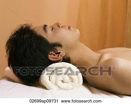 Stock Image - young man getting a spa massage feeling relaxed. Fotosearch