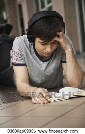 young man reading a book while listening to music View Large Photo Image Stock Photography - young man reading a book while listening to music. Fotosearch
