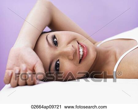 "young woman lying down facing camera, smiling sweetly" View Large Photo Image Stock Image - "young woman lying down facing camera, smiling sweetly". Fotosearch
