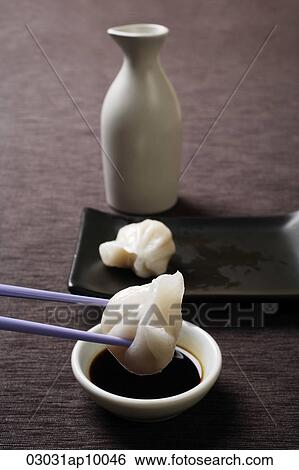 Stock Photograph - chopstick dipping dim sum in soy sauce. Fotosearch