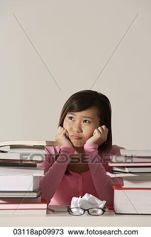 Young woman sitting at desk with books looking sad. View Large Photo Image Stock Image - Young woman sitting at desk with books looking sad.. Fotosearch