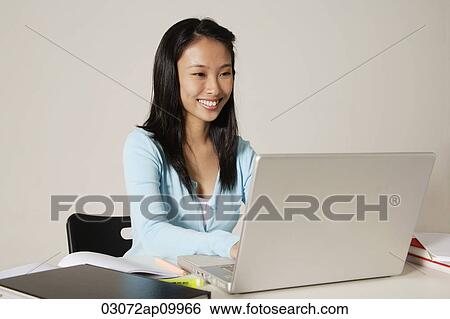Stock Photograph - young woman working on desk. Fotosearch