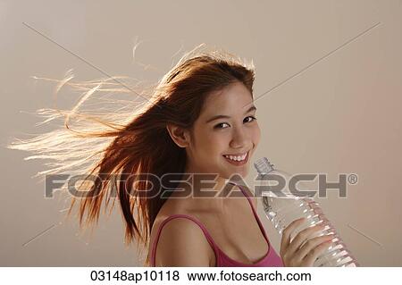 Stock Photo - Asian girl holding bottle water with hair blowing. Fotosearch