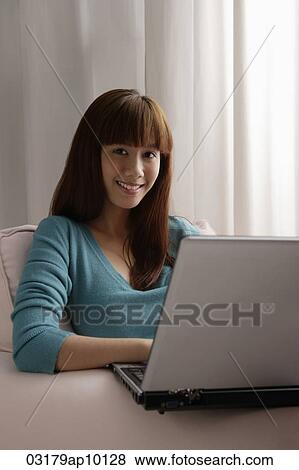 Asian girl working on laptop at home View Large Photo Image Stock Photo - Asian girl working on laptop at home. Fotosearch
