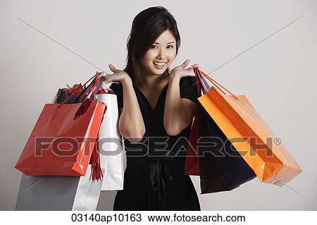 Chinese woman holding shopping bags, smiling View Large Photo Image Stock Image - Chinese woman holding shopping bags, smiling. Fotosearch