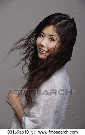 Stock Image - Chinese woman with long hair, smiling. Fotosearch