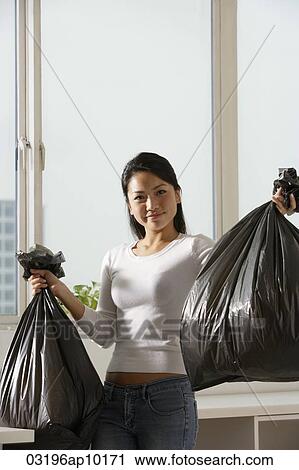 Young Asian woman holding up trash bags View Large Photo Image Stock Image - Young Asian woman holding up trash bags. Fotosearch