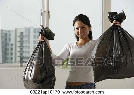 Young Asian woman holding up trash bags View Large Photo Image Stock Image - Young Asian woman holding up trash bags. Fotosearch