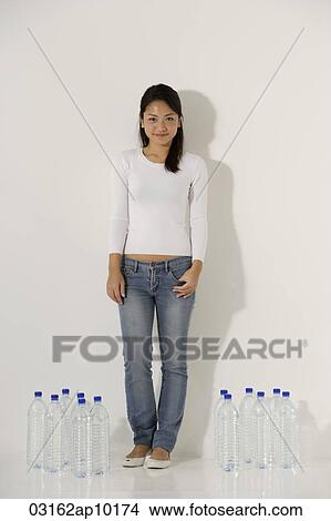 Young Asian woman standing near water bottles View Large Photo Image Picture - Young Asian woman standing near water bottles. Fotosearch