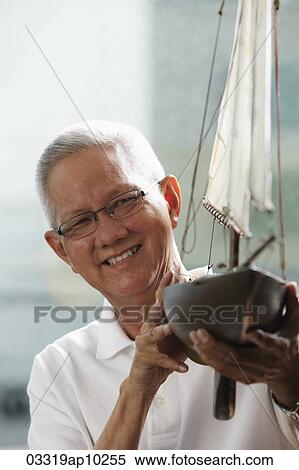 head shot of mature man holding model sail boat and smiling View Large Photo Image Stock Photography - head shot of mature man holding model sail boat and smiling. Fotosearch