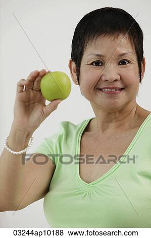 Mature Chinese woman holding green apple and smiling View Large Photo Image Stock Photo - Mature Chinese woman holding green apple and smiling. Fotosearch