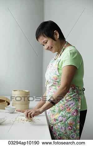 Stock Image - Mature Chinese woman making Dim Sum. Fotosearch
