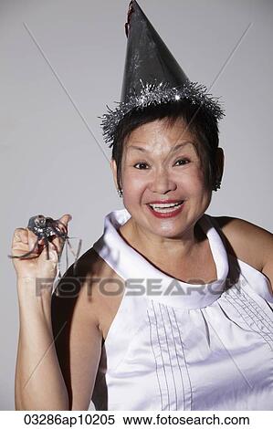 Stock Photography - Mature Chinese woman wearing a party hat and smiling. Fotosearch