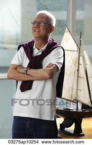 mature man folding his arms and smiling in front of model sail boat View Large Photo Image Picture - mature man folding his arms and smiling in front of model sail boat. Fotosearch