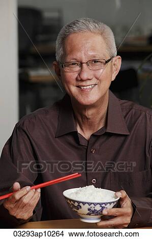 mature man holding chopsticks and bowl of rice and smiling View Large Photo Image Picture - mature man holding chopsticks and bowl of rice and smiling. Fotosearch