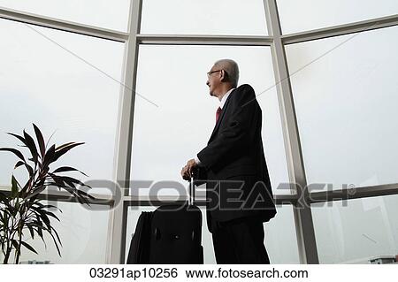 mature man looking out the window and holding luggage View Large Photo Image Stock Photograph - mature man looking out the window and holding luggage. Fotosearch