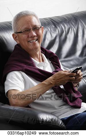 Stock Photo - mature man with grey hair smiling holding a phone. Fotosearch
