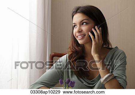 young woman talking on phone looking out window View Large Photo Image Stock Photo - young woman talking on phone looking out window. Fotosearch