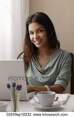 young woman working on a laptop at a cafe View Large Photo Image Stock Image - young woman working on a laptop at a cafe. Fotosearch