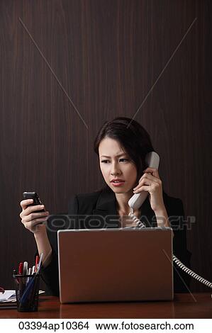 Stock Photo - Woman sitting at her desk multi-tasking. Fotosearch - Search Stock Images, Mural Photographs, Pictures, and Clipart Photos