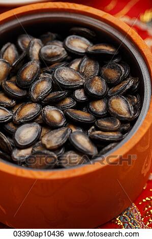Stock Photograph - Black melon seeds in orange bowl. Fotosearch
