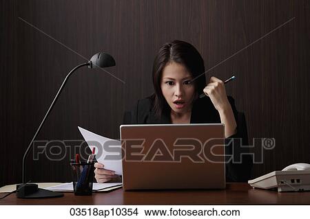 Picture - Chinese woman looking at computer on shock. Fotosearch