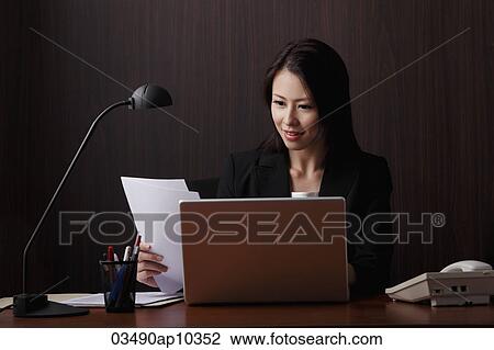 Chinese woman sitting at desk looking at papers View Large Photo Image Stock Image - Chinese woman sitting at desk looking at papers. Fotosearch