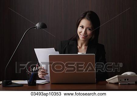 Chinese woman sitting at desk smiling View Large Photo Image Stock Image - Chinese woman sitting at desk smiling. Fotosearch