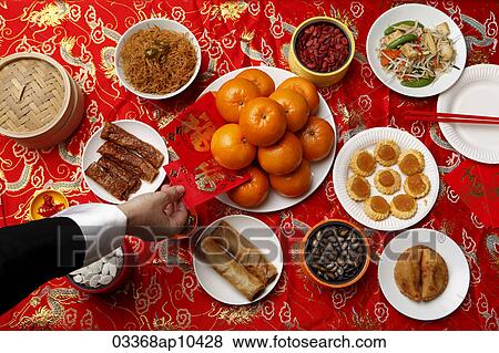 Hand reaching for red envelope (Hong Bao) on table set for Chinese New Year. View Large Photo Image Stock Photo - Hand reaching for red envelope (Hong Bao) on table set for Chinese New Year.. Fotosearch