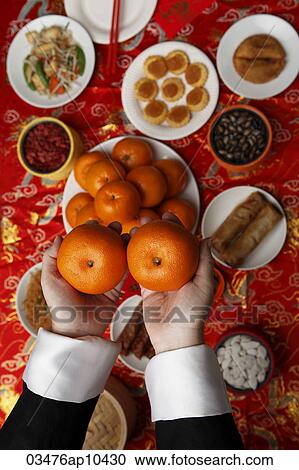 Hands holding oranges over table with Chinese food View Large Photo Image Stock Image - Hands holding oranges over table with Chinese food. Fotosearch