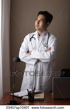 male doctor standing at his desk looking out window View Large Photo Image Stock Image - male doctor standing at his desk looking out window. Fotosearch