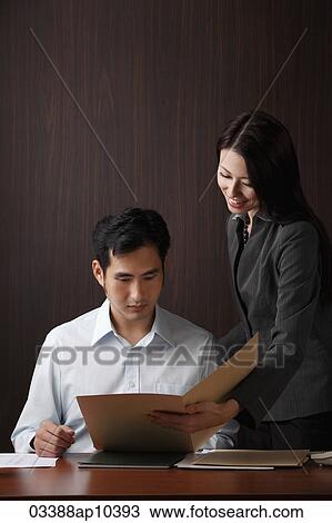 Stock Image - Man and woman looking at folder. Fotosearch