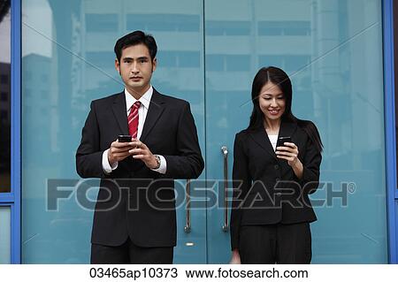 Man and woman wearing suits holding phones View Large Photo Image Stock Image - Man and woman wearing suits holding phones. Fotosearch